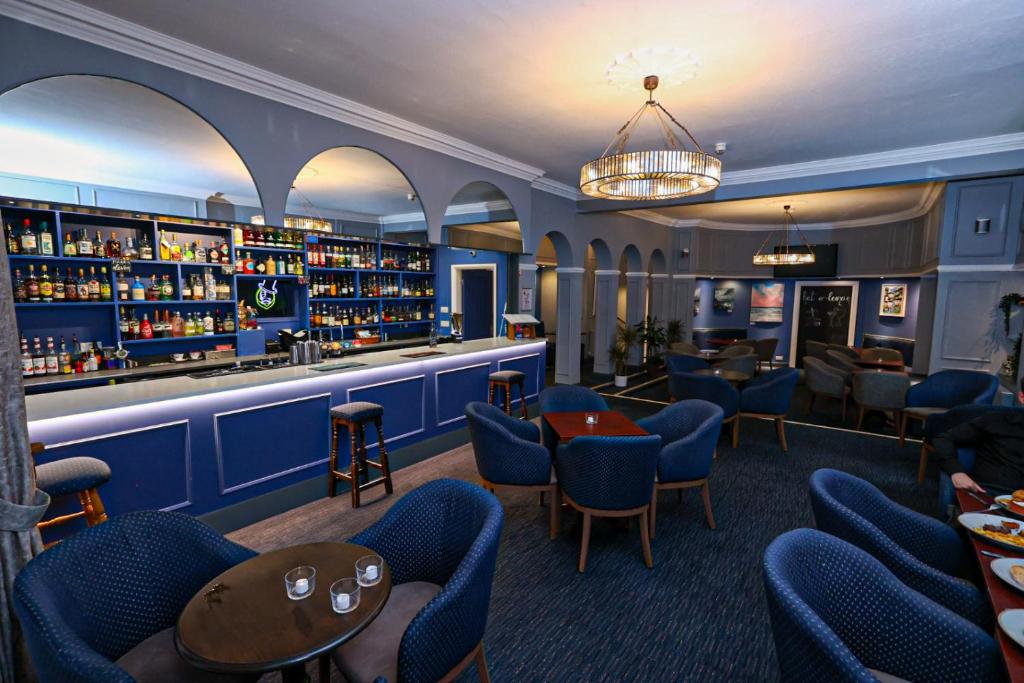 a bar in a restaurant with blue chairs and shelves at Manor Hotel in Exmouth