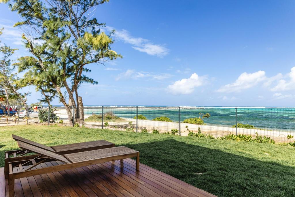 um deque de madeira com um banco e vista para o oceano em Ocean Terraces Apt A1 - Your Beachfront Bliss - Brand NEW em Poste Lafayette