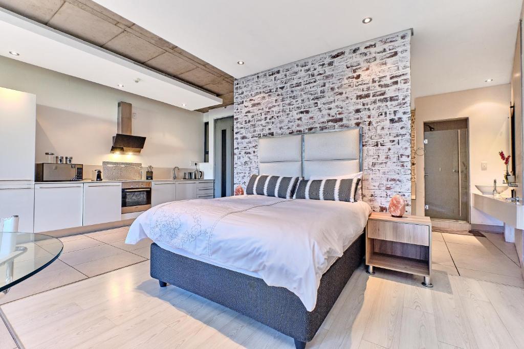 ein Schlafzimmer mit einem großen Bett und einer Ziegelwand in der Unterkunft Studio Apartment In Melrose Arch in Johannesburg