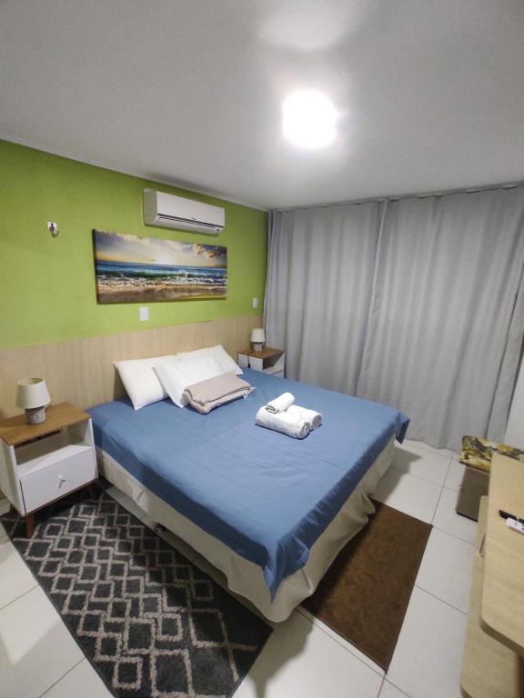 a bedroom with a blue bed and a green wall at Flat Manaíra Palace in João Pessoa