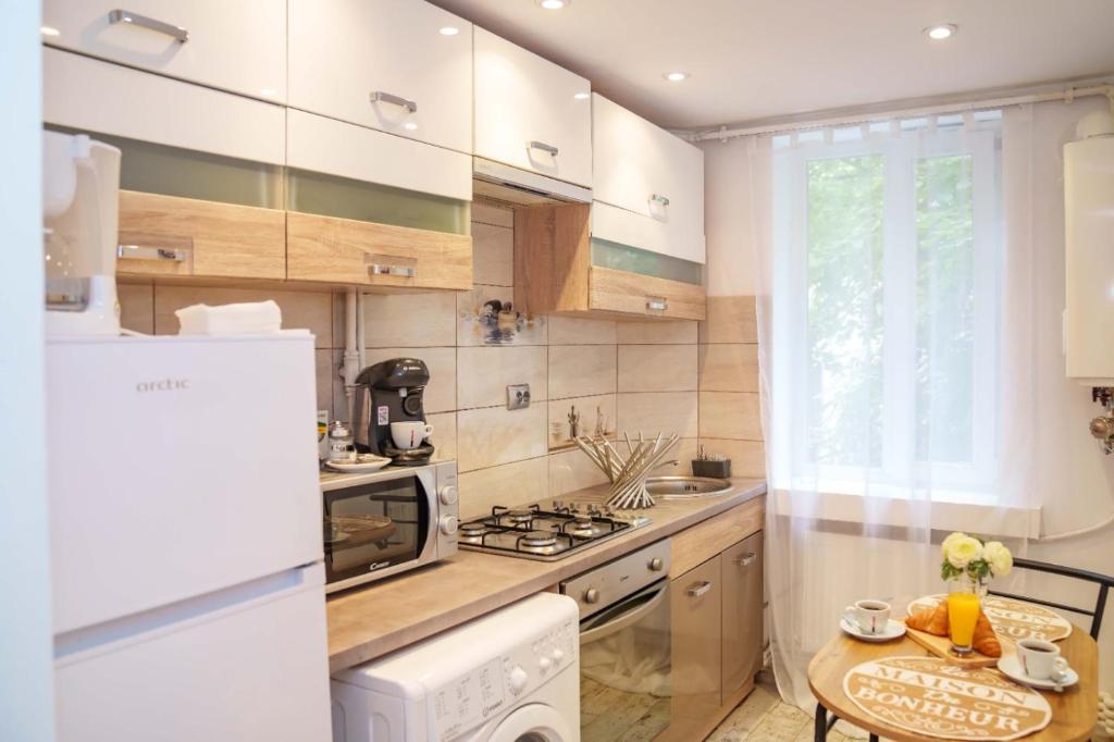 uma cozinha com electrodomésticos brancos e uma mesa em L'escale - Ultracentral em Craiova