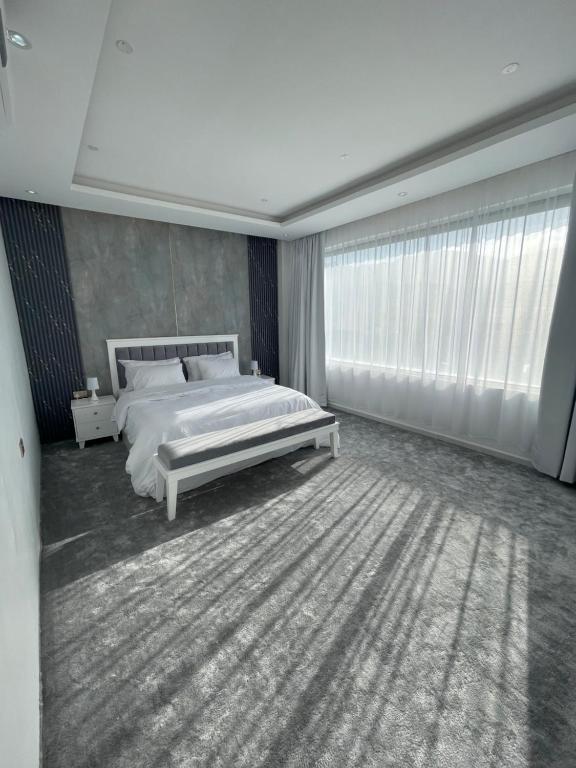 um quarto com uma cama branca e uma grande janela em Al ATLAL apartment em Nizwa
