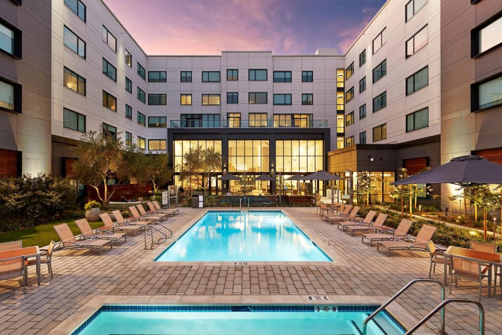 a hotel with a pool and chairs and a building at Element Santa Clara in Santa Clara