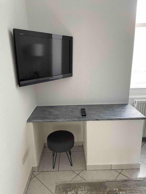 a desk with a television on a wall with a chair at Cocooning in Colmar