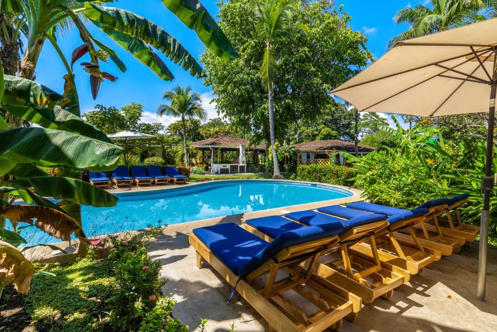 a swimming pool with lounge chairs and an umbrella at Hotel Bahia Esmeralda in Potrero