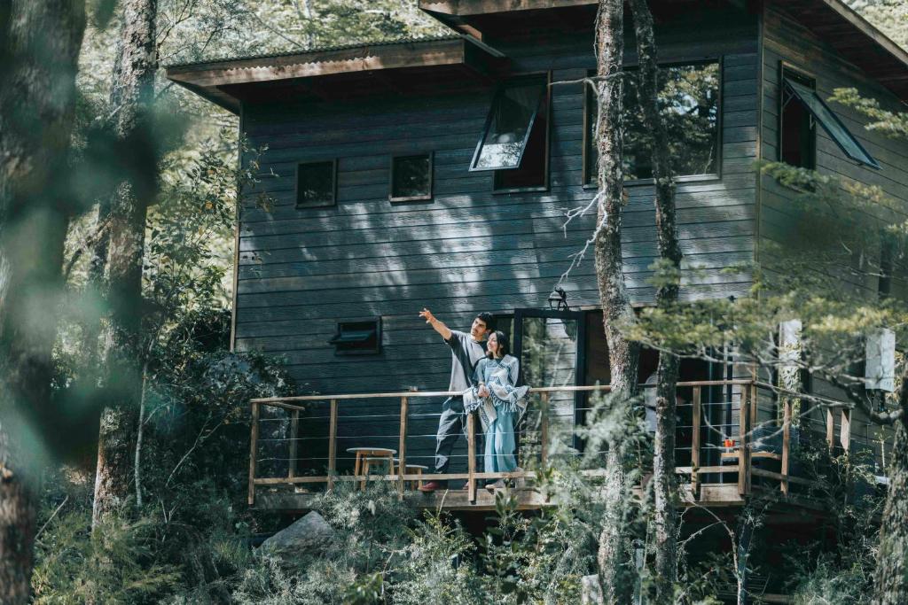 un homme et une femme debout sur la terrasse couverte d'une maison dans l'établissement RUKAKUTRAL refugio de bosque, à Pucón