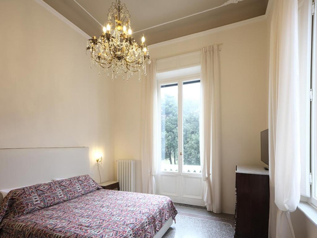 a bedroom with a bed and a chandelier and a window at Villa Giulia BnB in Viareggio