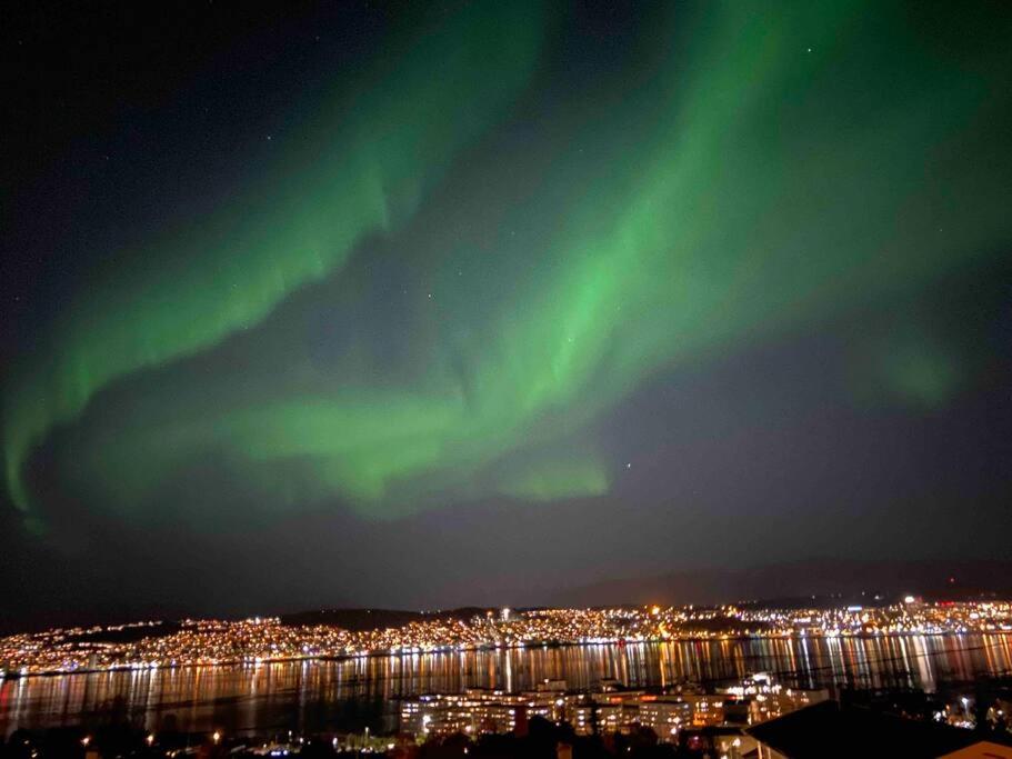 une aurore dans le ciel au-dessus d'une ville la nuit dans l'établissement Fin leilighet i Tromsø, à Tromsø