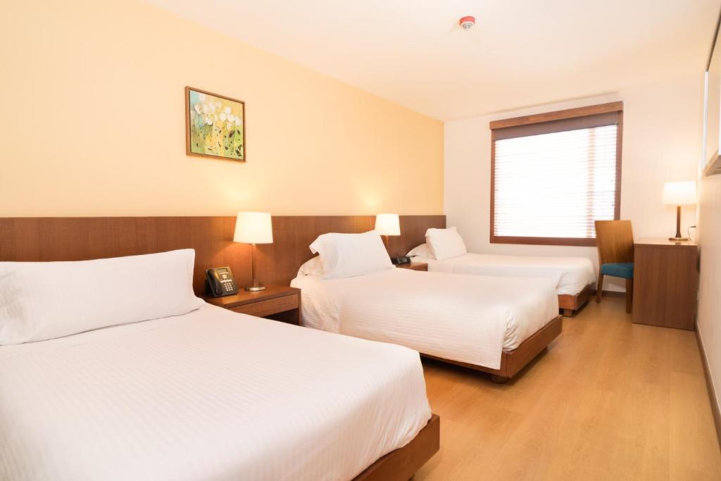 a hotel room with two beds and a window at Hotel Habitel Select in Bogotá