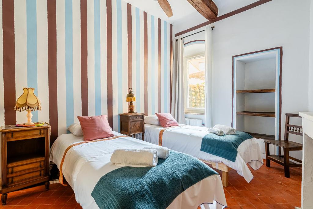 two beds in a room with striped walls at Casa Antoinette-Invitation vintage au-dessus du Vieux-Port in La Ciotat