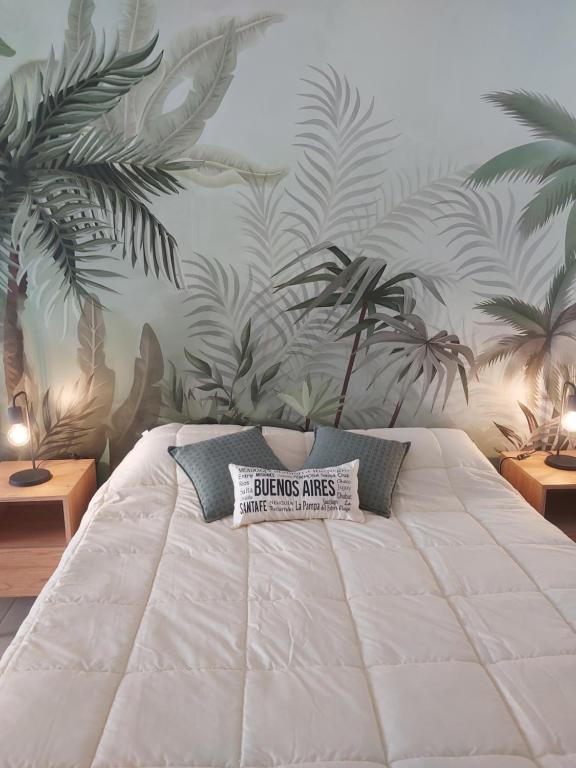 a bedroom with a large white bed with plants on the wall at Palmas de Recoleta in Buenos Aires