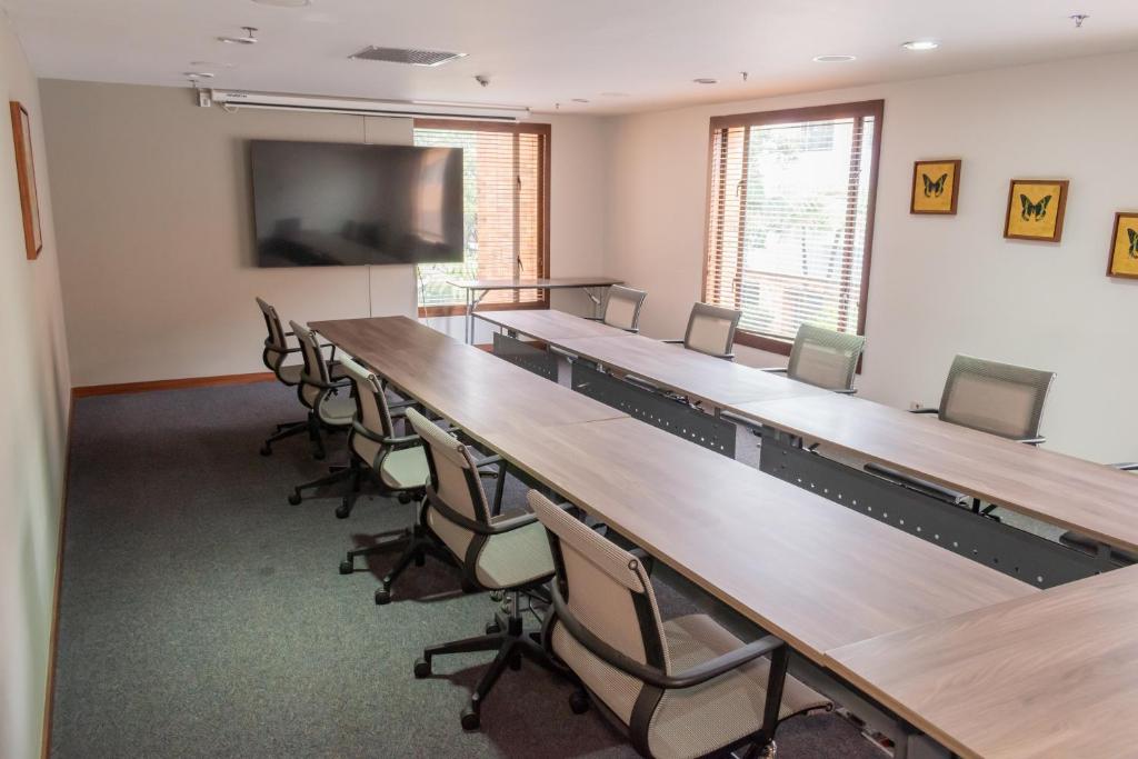 a classroom with tables and chairs and a flat screen tv at Hotel Habitel Select in Bogotá