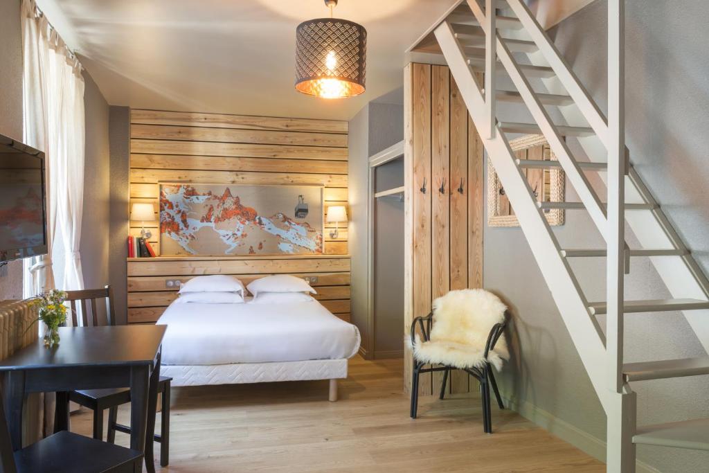 een slaapkamer met een bed, een trap en een tafel bij Hôtel de Russie in Le Mont-Dore