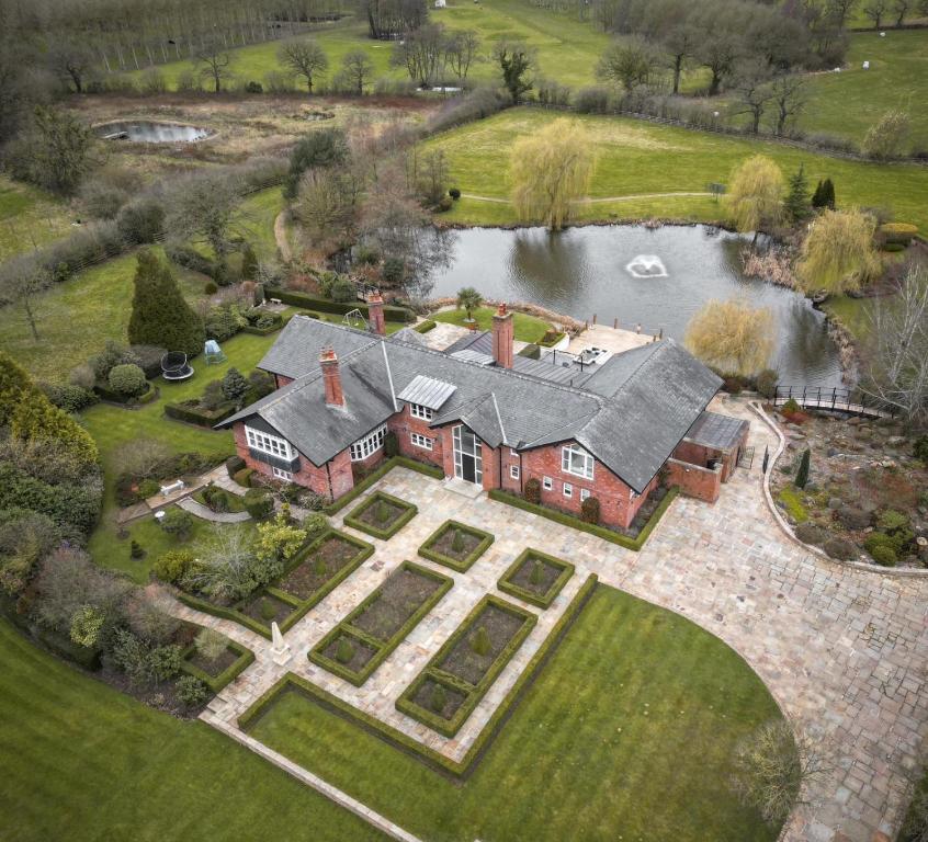 an aerial view of a large house with a pond at Fernside house and barns in Pickmere