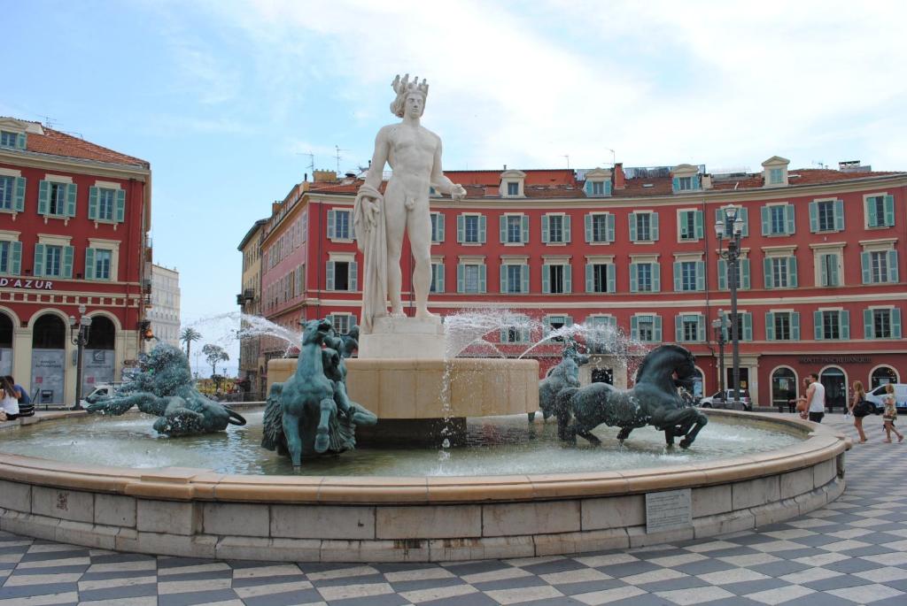 a statue of a man in a fountain in front of a building at Les Suites Massena in Nice