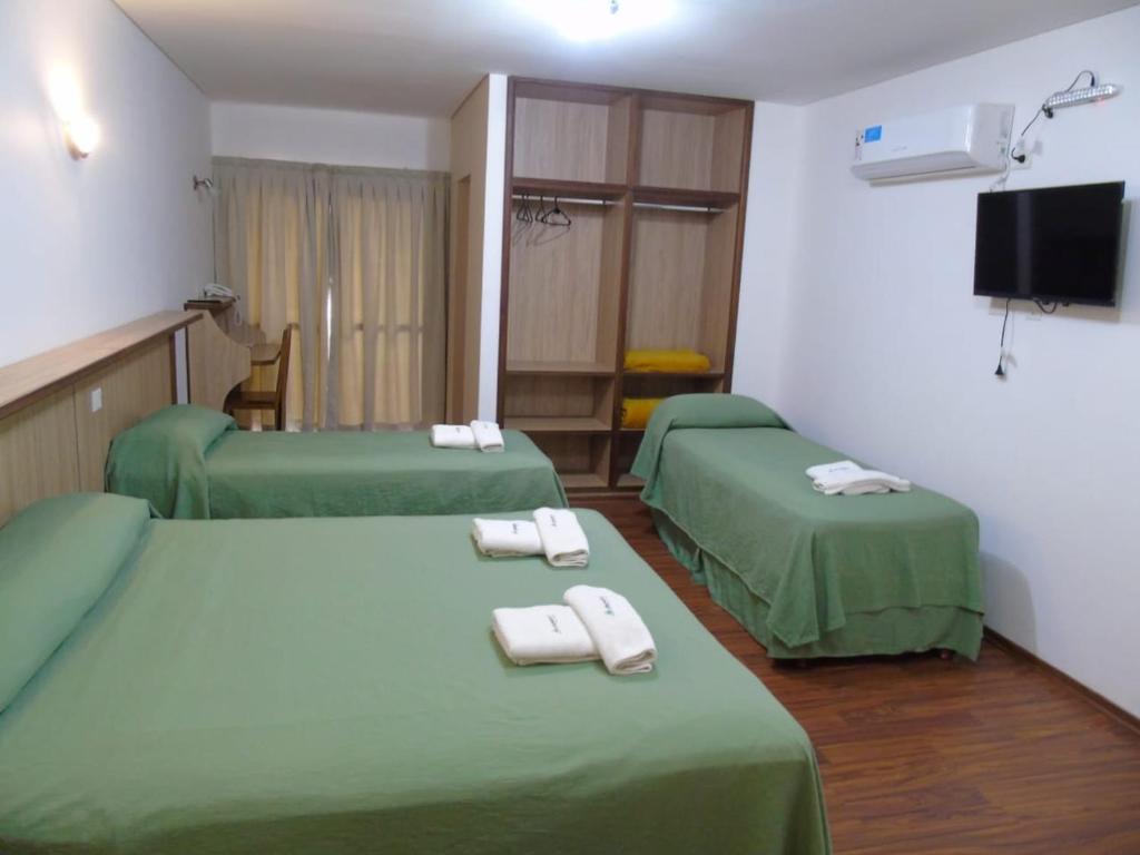 Habitación con 2 camas verdes y toallas. en Urunday Apart Hotel en Posadas
