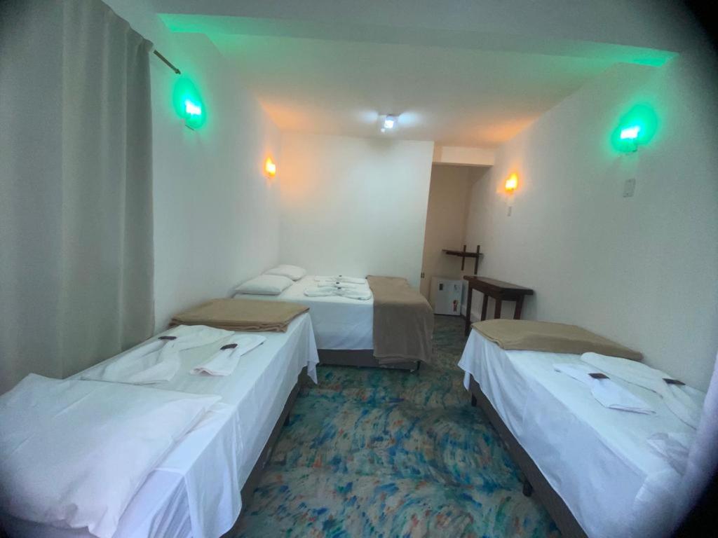 two beds in a hotel room with green lights at Pousada Flor de Debora in Alto Paraíso de Goiás