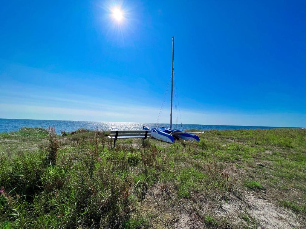 eine Bank am Strand mit einem Segelboot darauf in der Unterkunft Lovely cottage by the south coast in Trelleborg