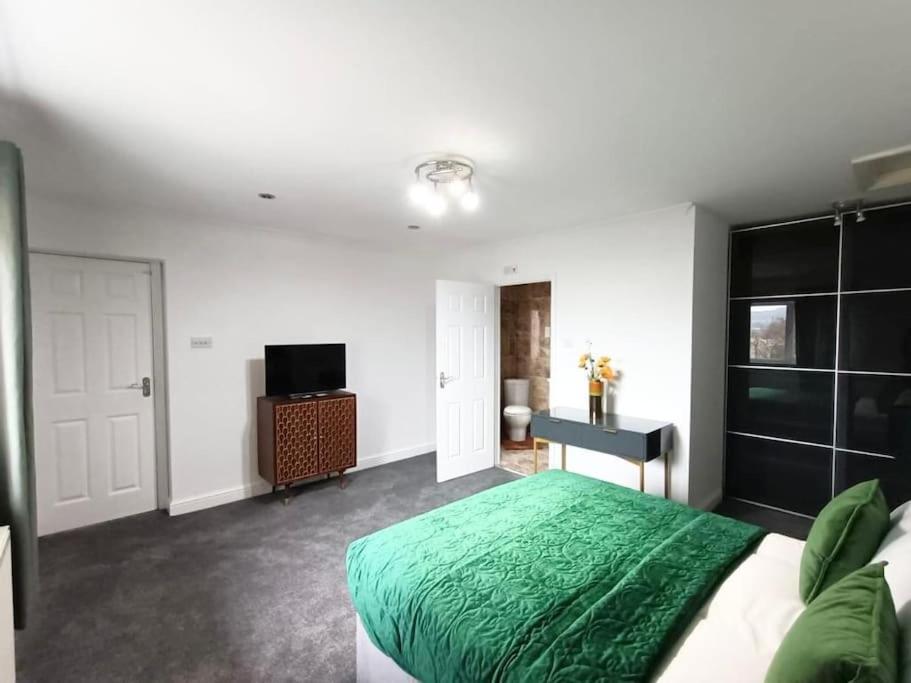 a bedroom with a green bed and a television at 4Bed House MK in Simpson