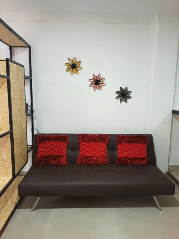 um sofá preto num quarto com duas aranhas na parede em HERMOSO APTO LA ESTRELLA em La Estrella
