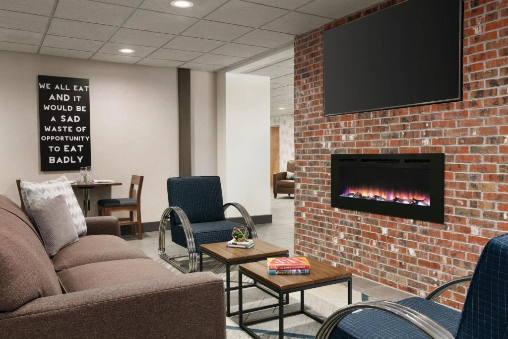 a waiting room with a fireplace and a tv on a brick wall at Four Points by Sheraton Raleigh Arena in Raleigh