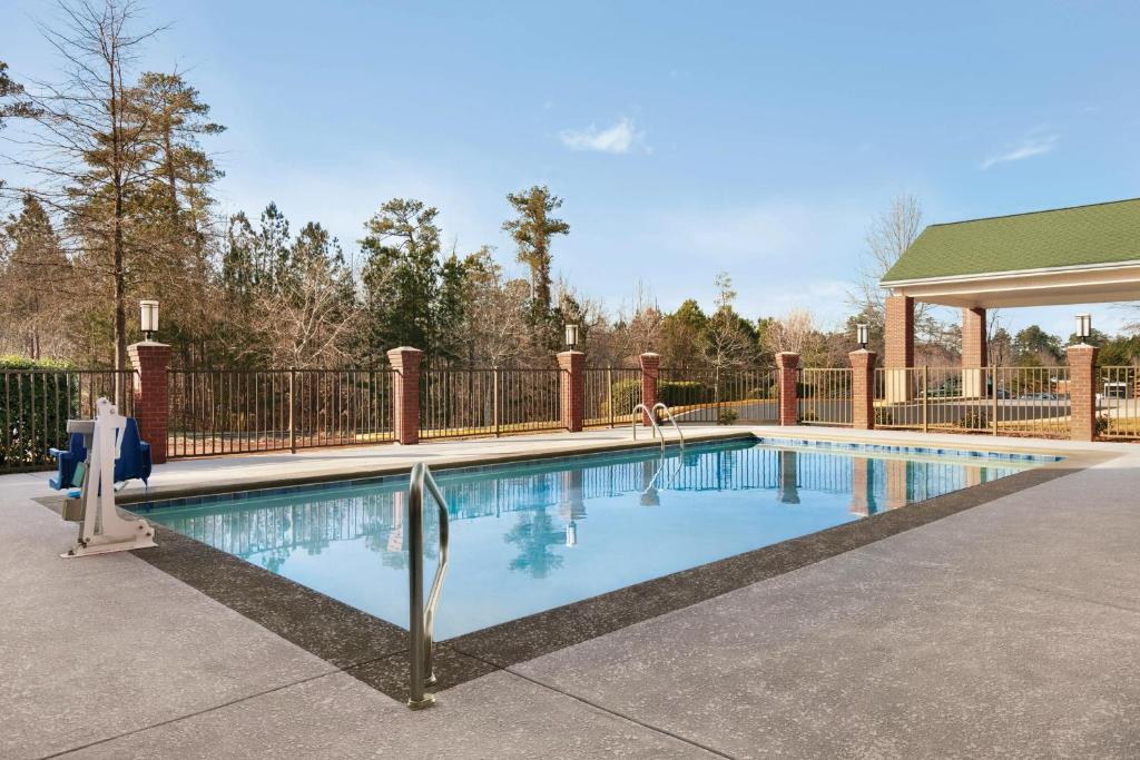 een zwembad in een tuin met een hek bij Four Points by Sheraton Raleigh Arena in Raleigh