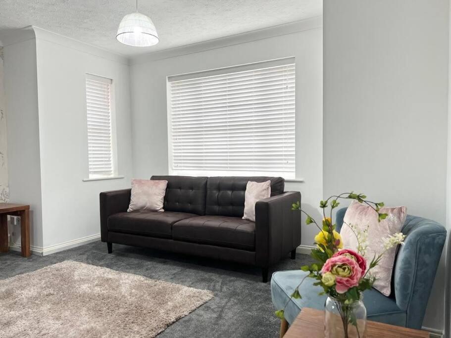 a living room with a black couch and a table at 4Bed Home MK in Shenley Brook End