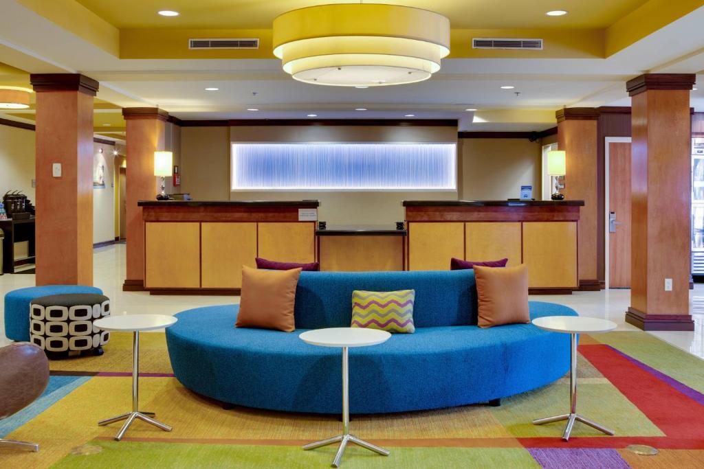Fairfield Inn and Suites by Marriott Titusville Kennedy Space Center في تيتوسفيل: غرفة معيشة مع أريكة زرقاء وطاولات