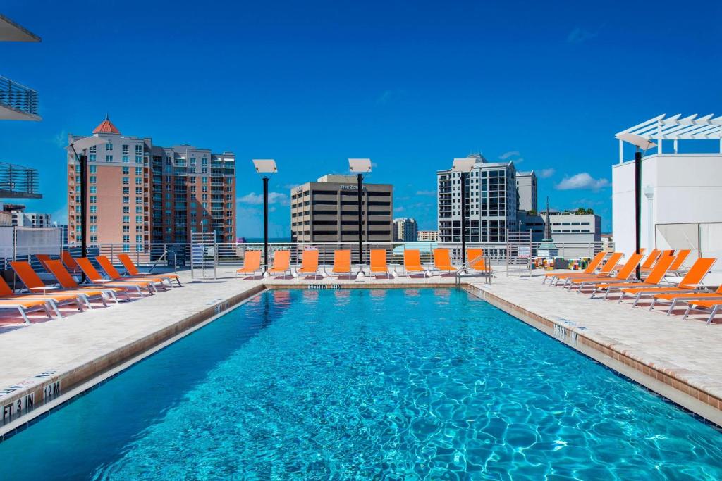 a swimming pool with chairs and a city skyline at Aloft Sarasota in Sarasota