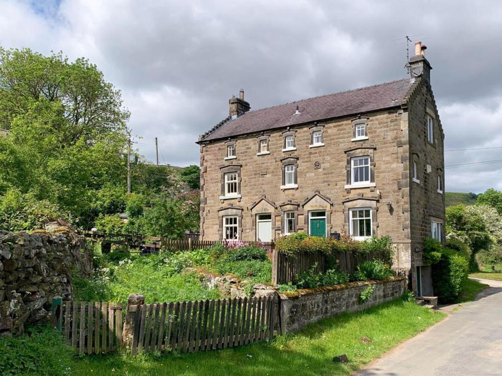 an old brick house with a fence in front of it at Primrose Villa in Rosedale Abbey