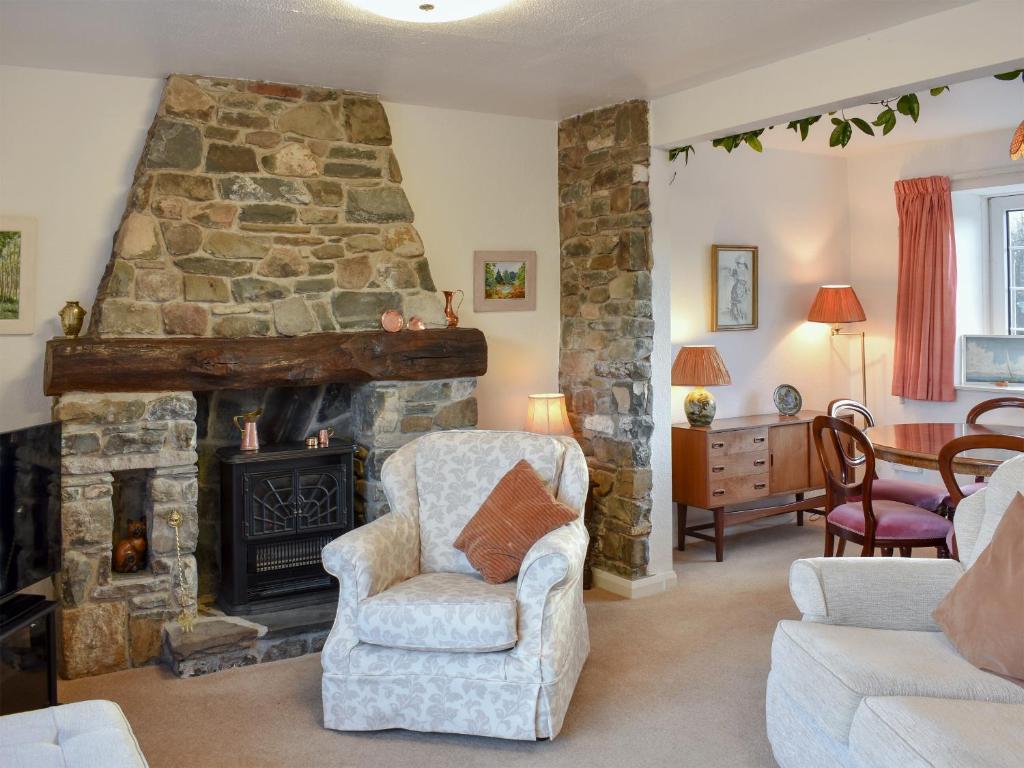 a living room with a stone fireplace and chairs at The Bothy in Old Hutton