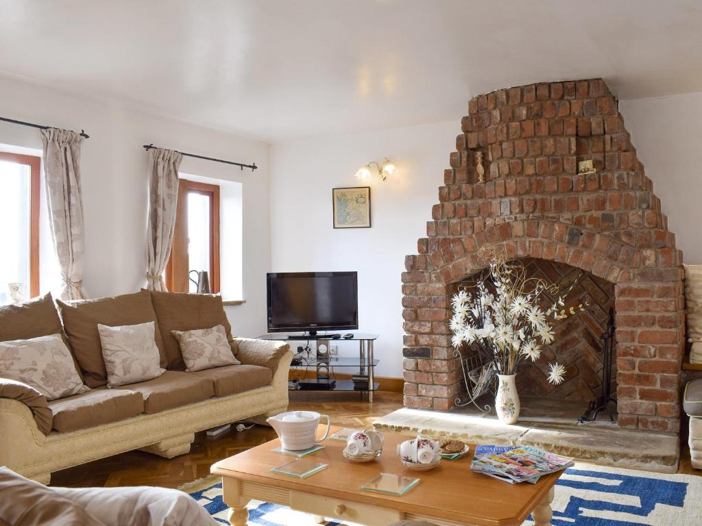 a living room with a couch and a brick fireplace at High Gate - Uk30579 in Nelson