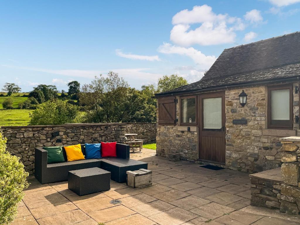 a patio with a couch with colorful pillows on it at Ravenscliffe Cottage in Tissington