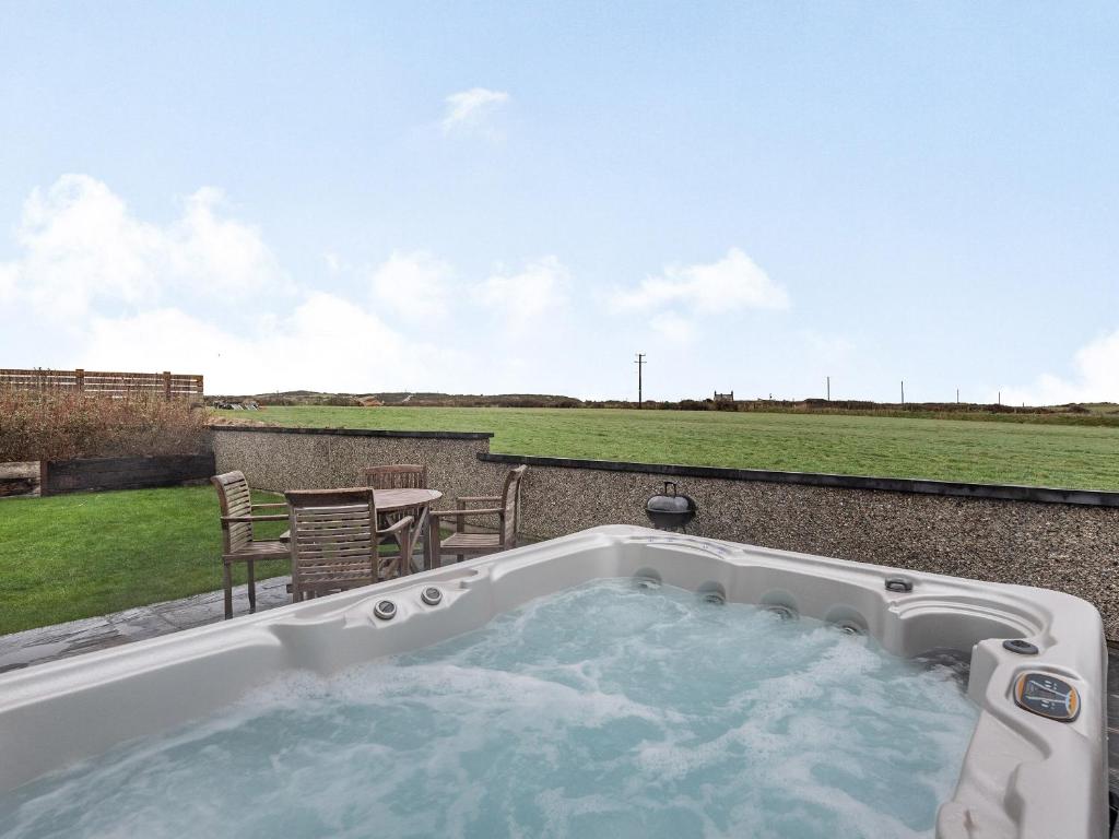 a hot tub on a patio with a table and chairs at Primrose Cottage in Holyhead