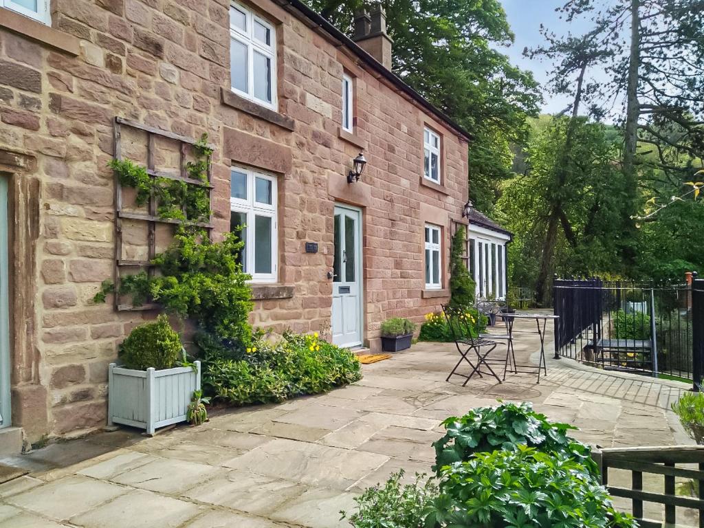 a brick house with a patio in front of it at Acacia Cottage in Wirksworth