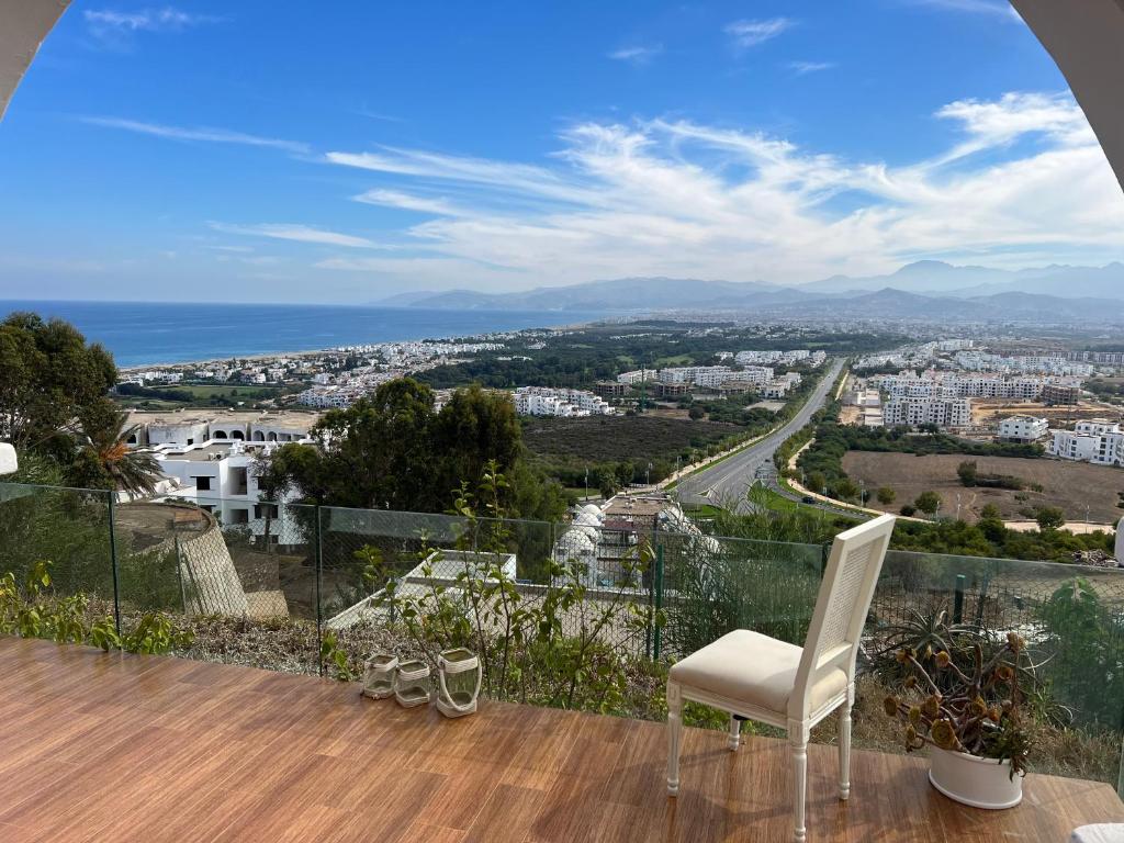 a balcony with a white chair and a view of the city at Luxueux VILLA avec jardin et vue panoramique in Tetouan