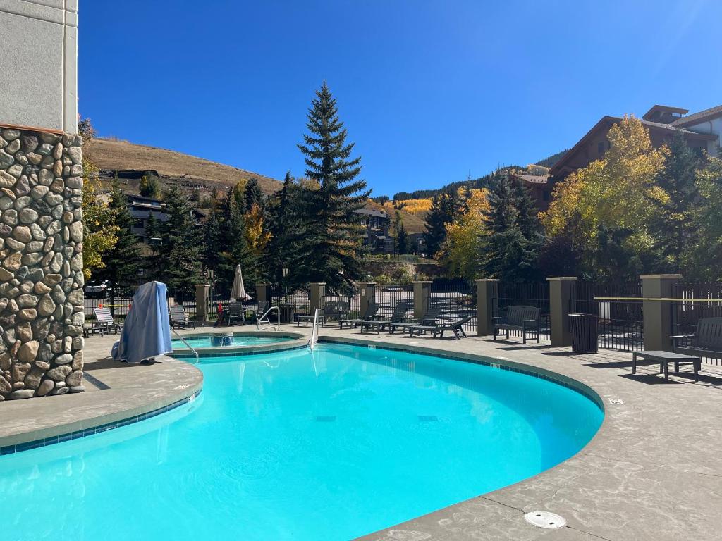 a swimming pool with blue water in a resort at MT CB Base Area with King Bed, Outdoor Hot Tub & Pool in Crested Butte