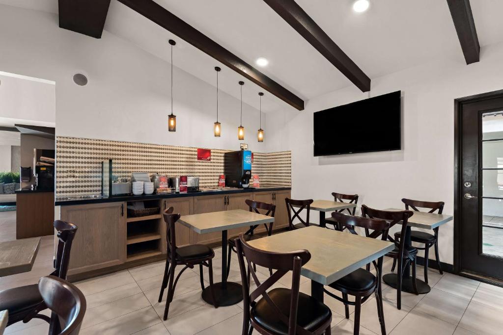 a dining room with tables and chairs and a tv at Best Western Plus Manhattan Beach Hotel in Manhattan Beach