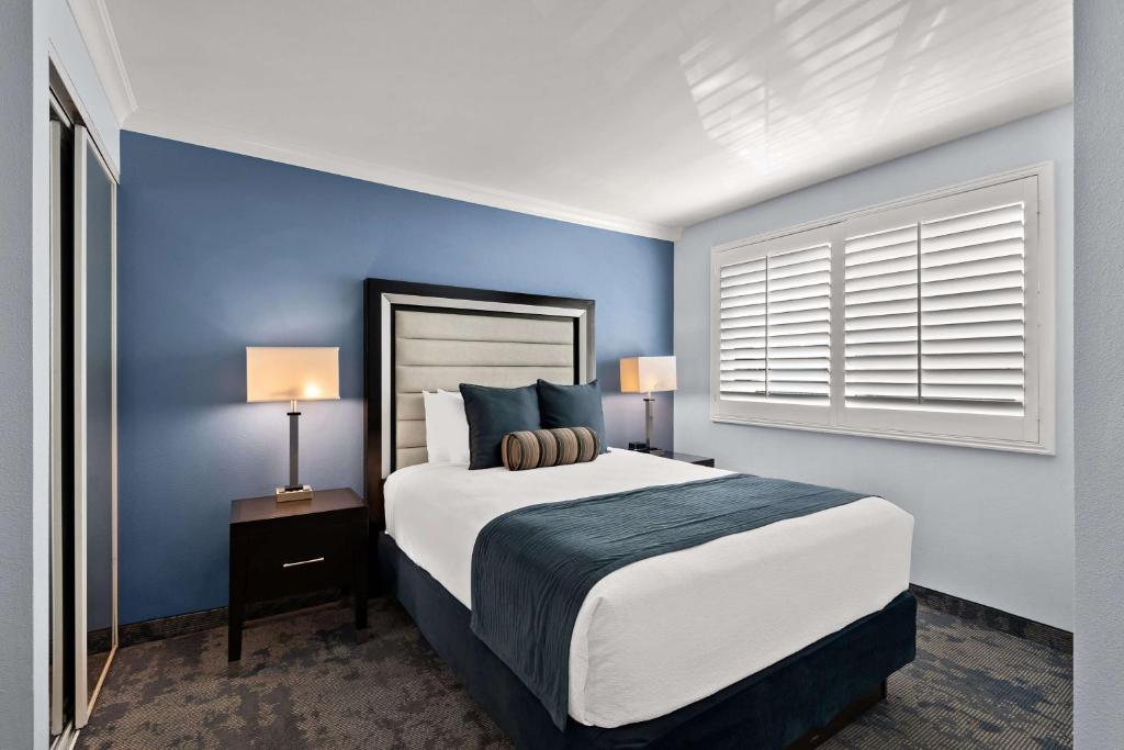 a bedroom with a large bed with blue walls at Best Western Plus Manhattan Beach Hotel in Manhattan Beach