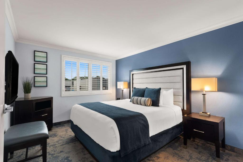 a bedroom with a large bed with blue walls at Best Western Plus Manhattan Beach Hotel in Manhattan Beach