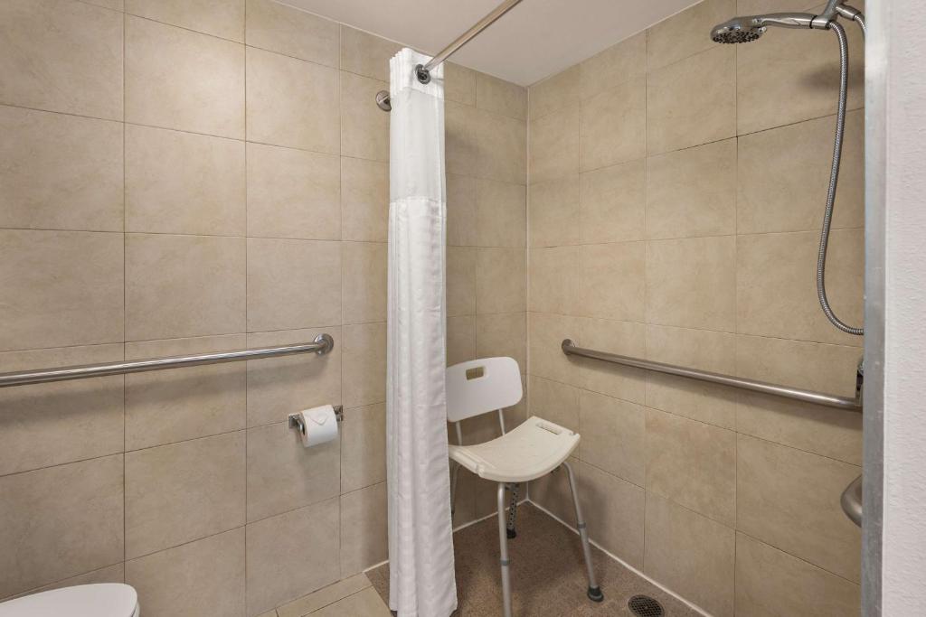 a bathroom with a shower with a toilet and a chair at Best Western Plus Manhattan Beach Hotel in Manhattan Beach
