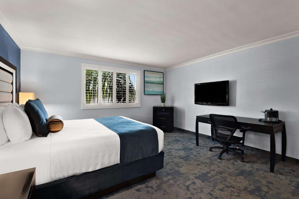 a hotel room with a bed and a desk with a computer at Best Western Plus Manhattan Beach Hotel in Manhattan Beach