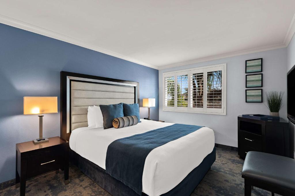 a bedroom with a large bed with blue walls at Best Western Plus Manhattan Beach Hotel in Manhattan Beach