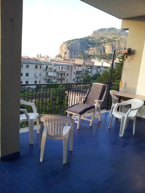 a balcony with chairs and tables and a view of a city at Le Giarette in Cefalù