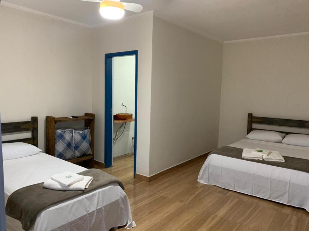 a room with two beds and a bathroom with a mirror at Pousada Fazendinha Alto da Serra in Serra Negra