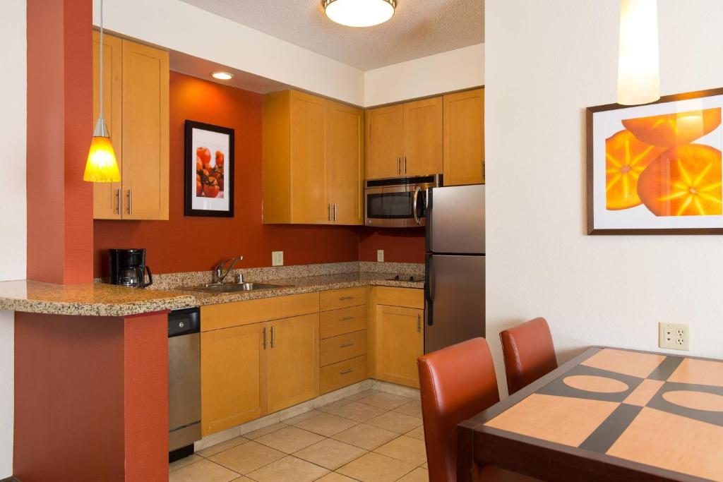 a kitchen with wooden cabinets and a table and a refrigerator at Residence Inn Kansas City Airport in Kansas City