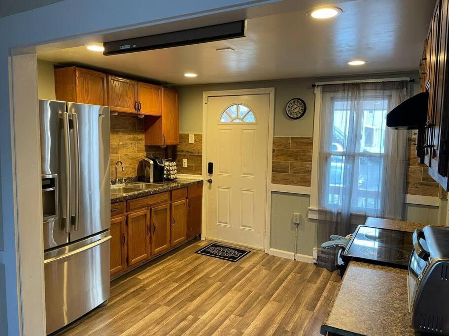 una cocina con armarios de madera y una puerta con nevera en Comfortable home away from home, en East Hartford