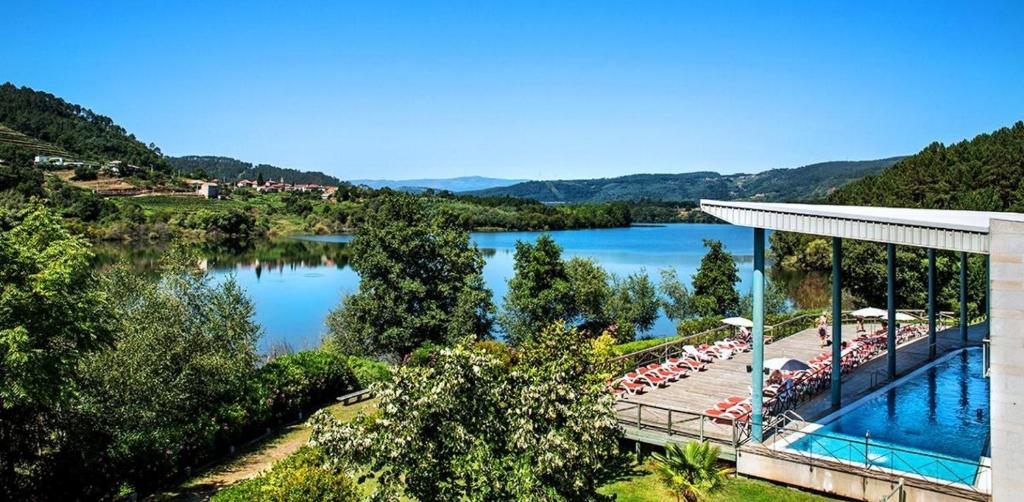 a pool with umbrellas and chairs next to a lake at Laias Caldaria hotel y Balneario in Laias