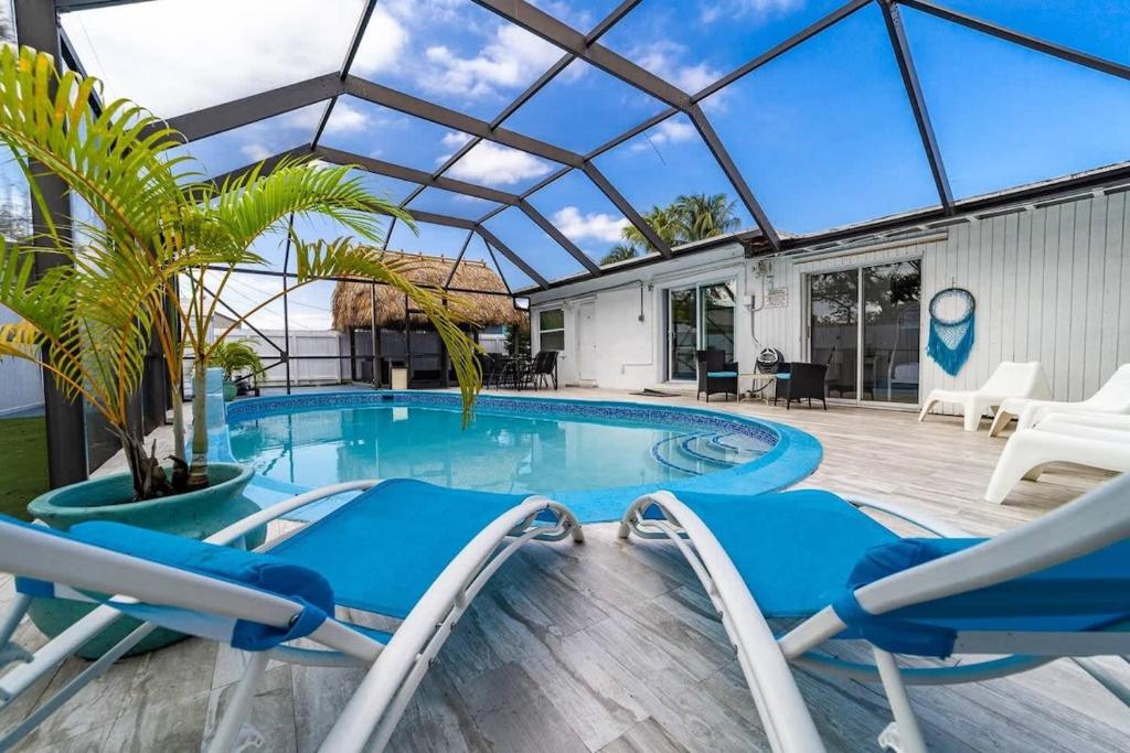 a swimming pool with blue chairs and a glass roof at Private Heated Pool Villa In Ftl Near Beach in Fort Lauderdale