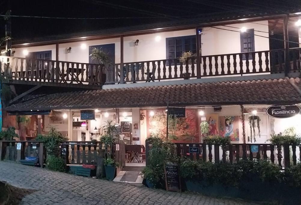 um edifício com uma varanda numa rua à noite em Casa 2 Cantina Florêncio São Pedro da Serra em Nova Friburgo